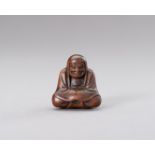 A WOOD NETSUKE OF DARUMA