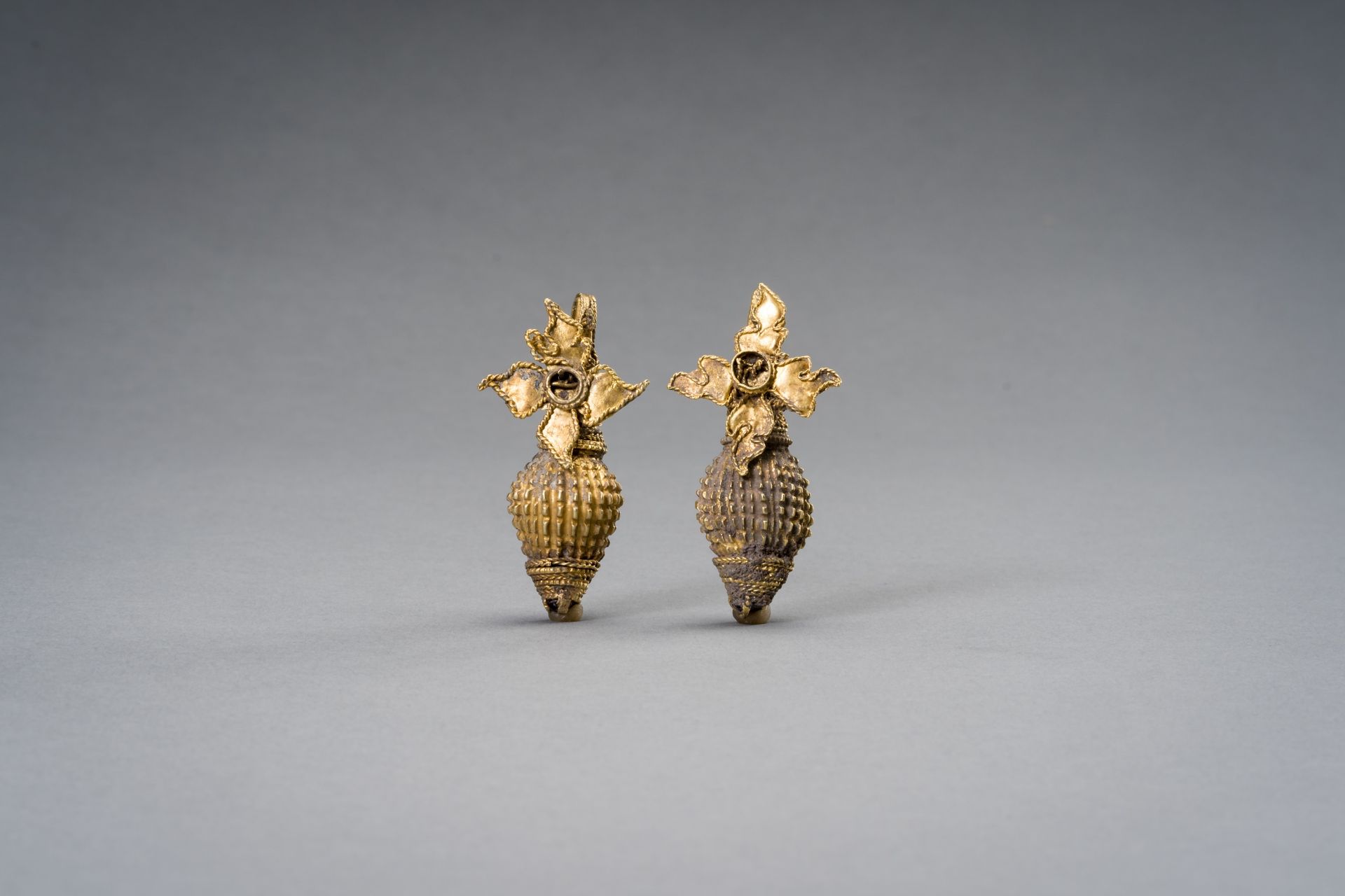 A PAIR OF INDIAN GOLD ORNAMENTS WITH CONCH AND FLOWER