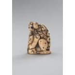 A STAG ANTLER NETSUKE OF A SHISHI ON A ROCK