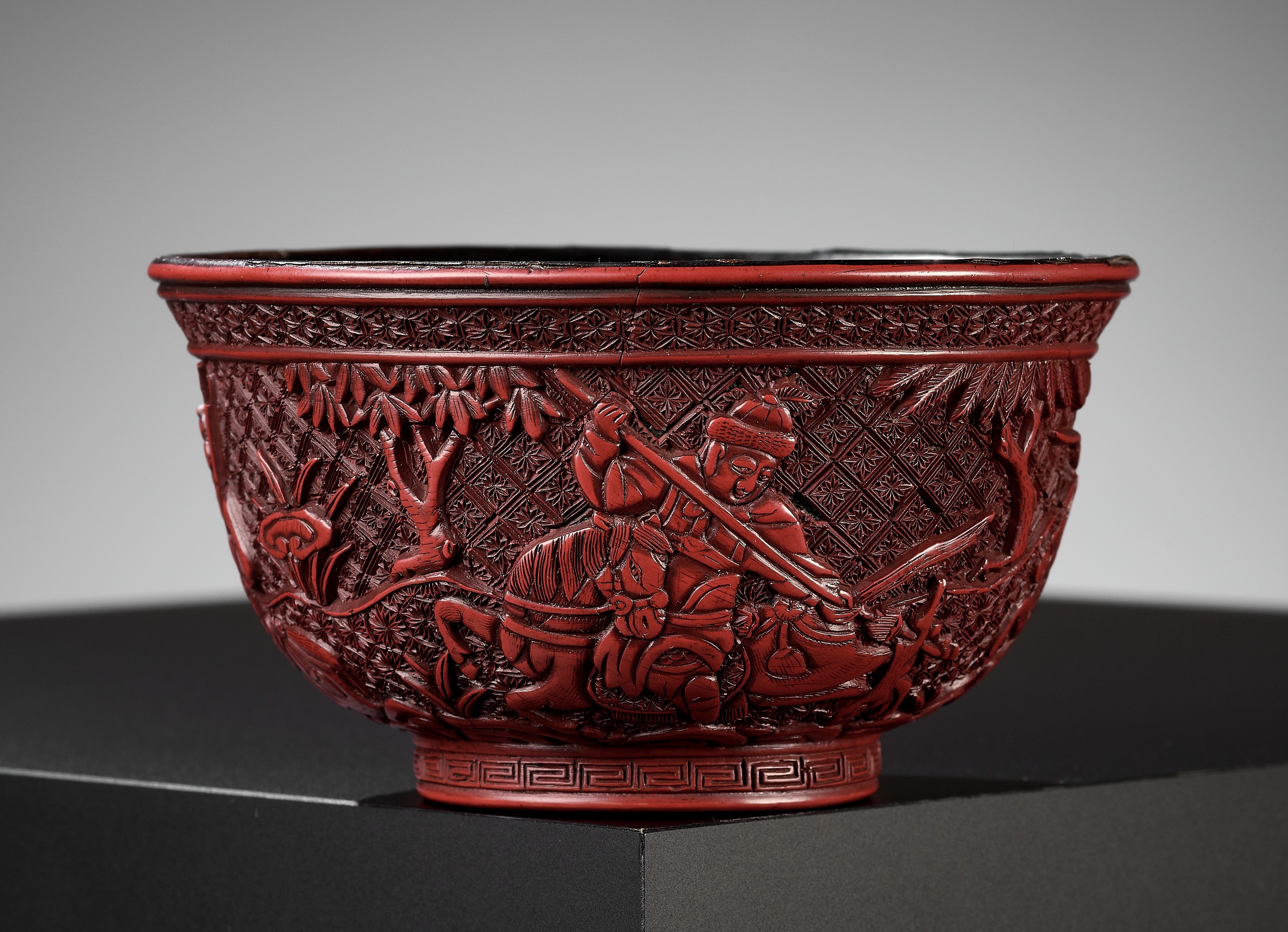 A RARE RED LACQUER 'MONGOL HUNT' BOWL, ATTRIBUTED TO ZHOU ZHU