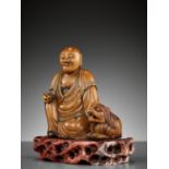 A SOAPSTONE FIGURE OF A LUOHAN WITH A BUDDHIST LION, 18TH CENTURY
