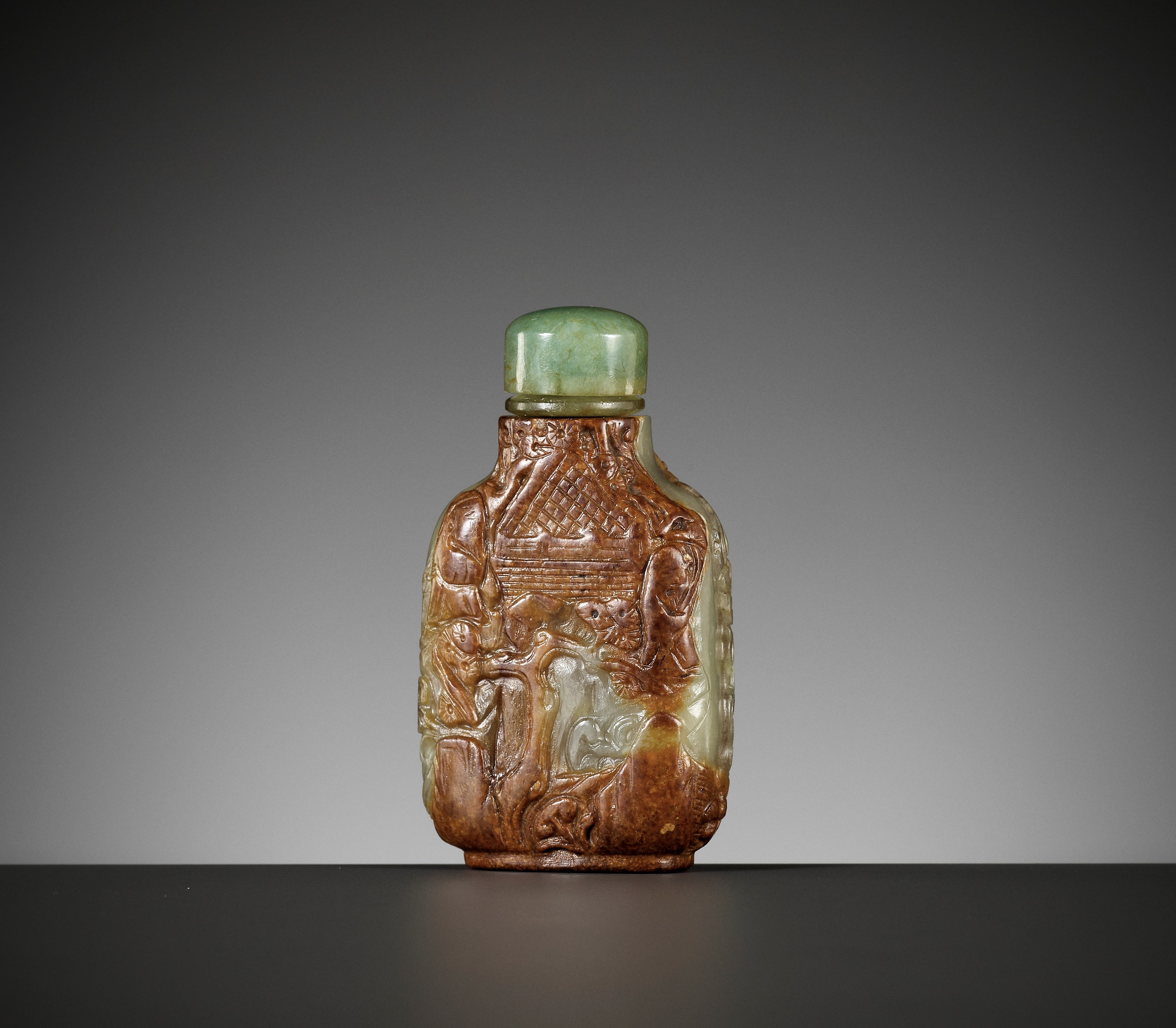 A CARVED CELADON AND RUSSET JADE SNUFF BOTTLE, MASTER OF THE ROCKS SCHOOL, 1740-1850