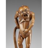 AN AMUSING WOOD NETSUKE OF A NAKED MAN TYING HIS FUNDOSHI