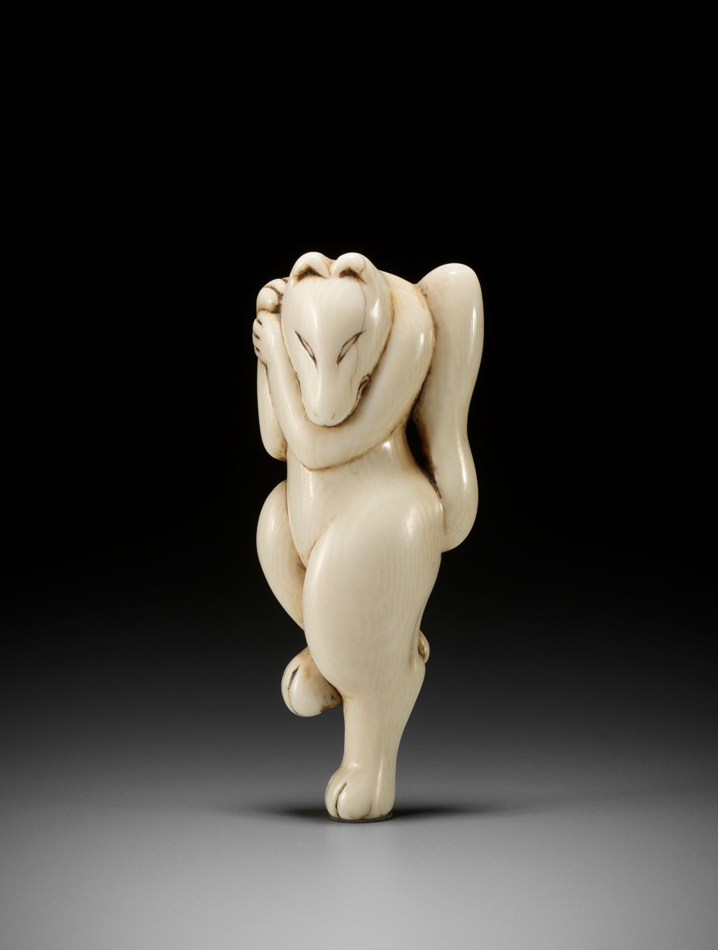 AN EARLY IVORY NETSUKE OF A DANCING KITSUNE