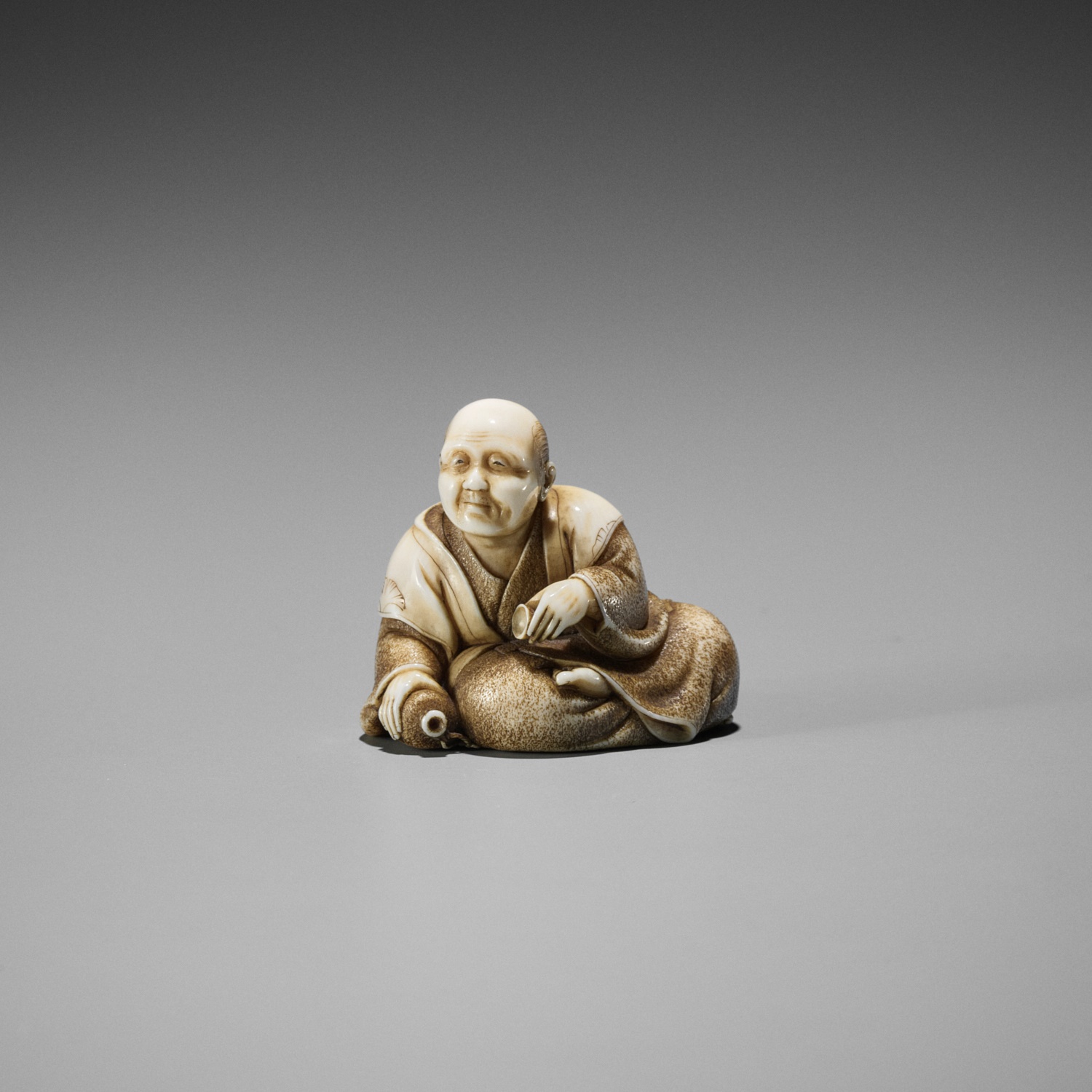 MUNETAME: A FINE IVORY NETSUKE OF A MAN DRINKING SAKE