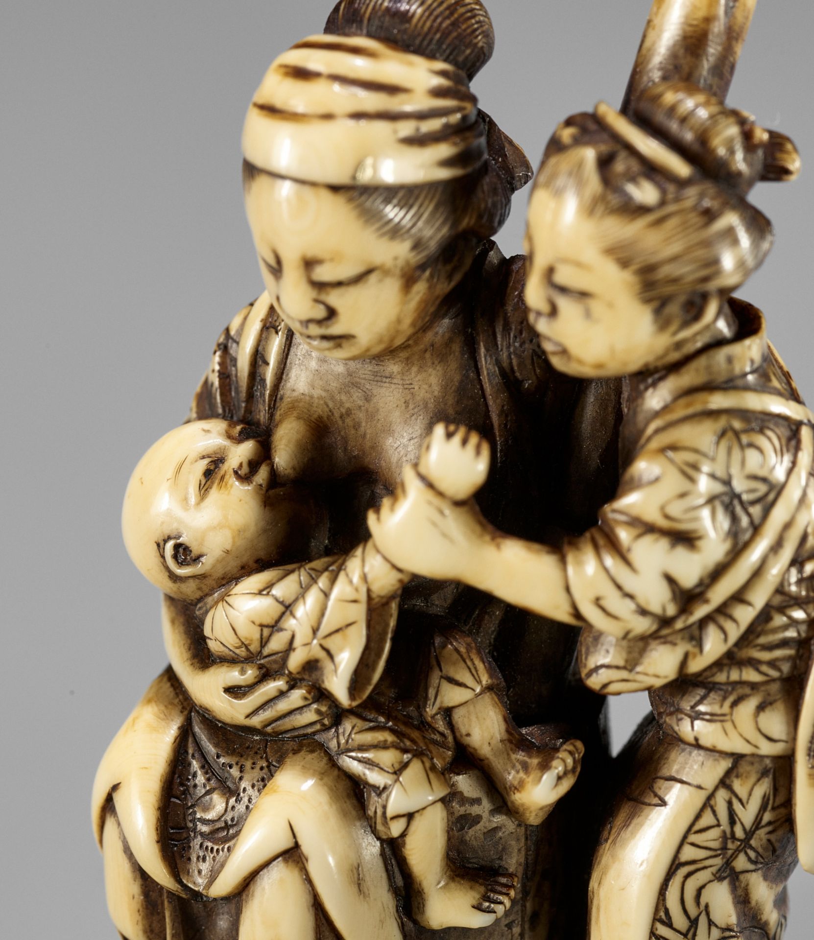 MINKOKU: A FINE IVORY NETSUKE OF TWO WOMEN WITH AN INFANT