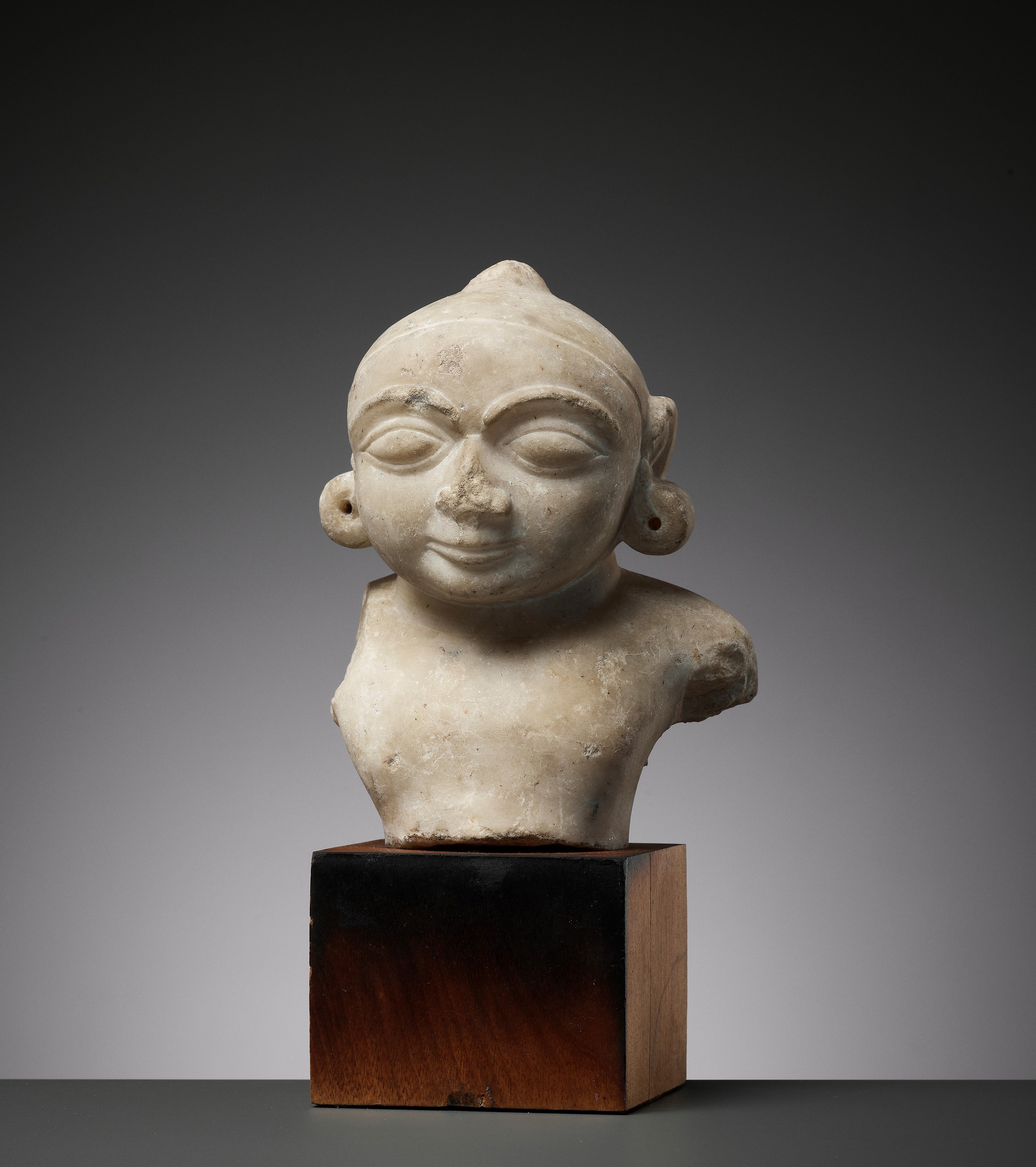 A JAIN WHITE MARBLE BUST OF THE CHILD KRISHNA, 14TH-15TH CENTURY