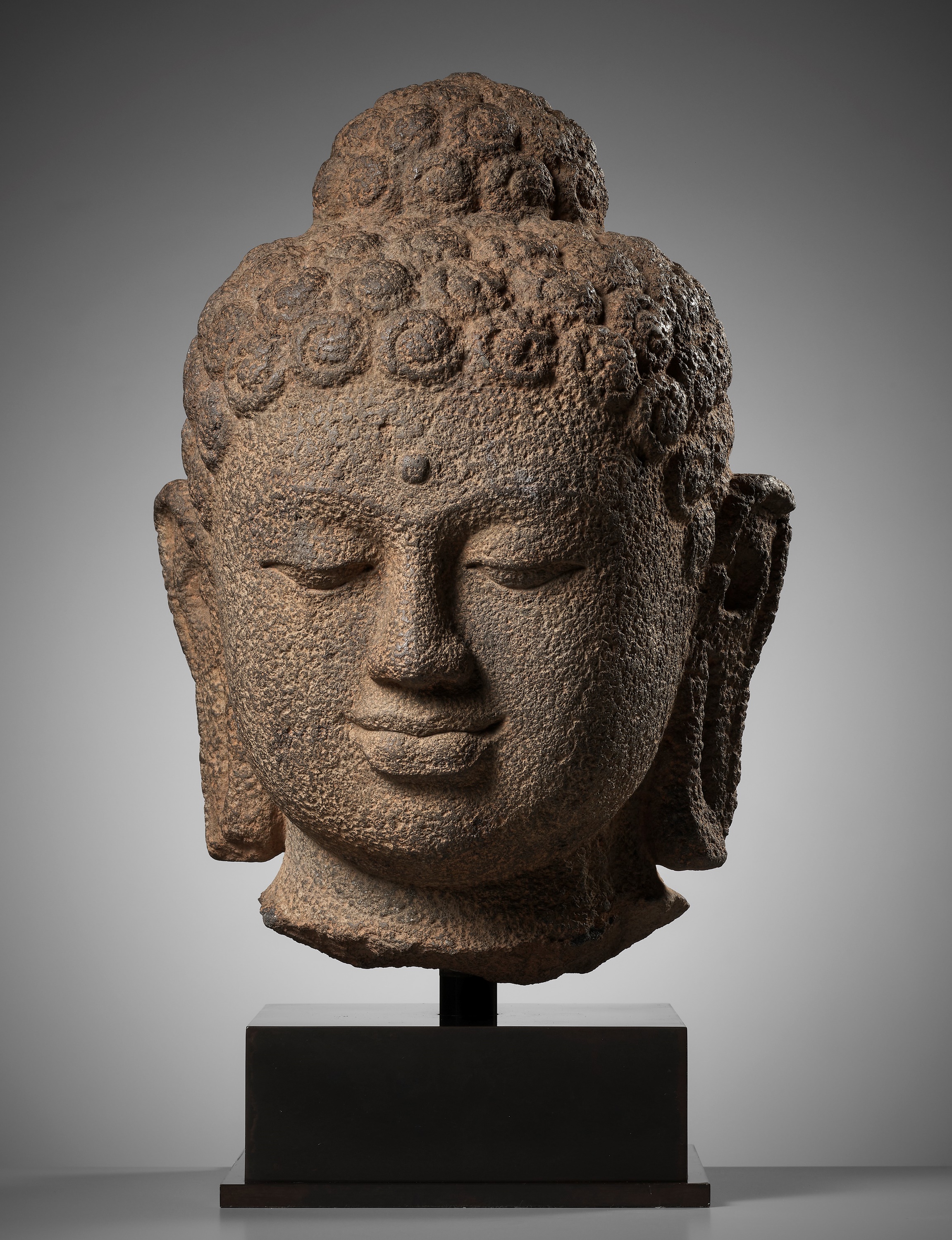 A LARGE ANDESITE HEAD OF BUDDHA, INDONESIA, CENTRAL JAVA, 9TH CENTURY