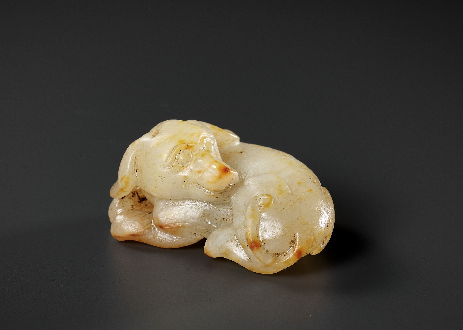 A PALE CELADON AND RUSSET JADE FIGURE OF A DOG, 17TH-18TH CENTURY