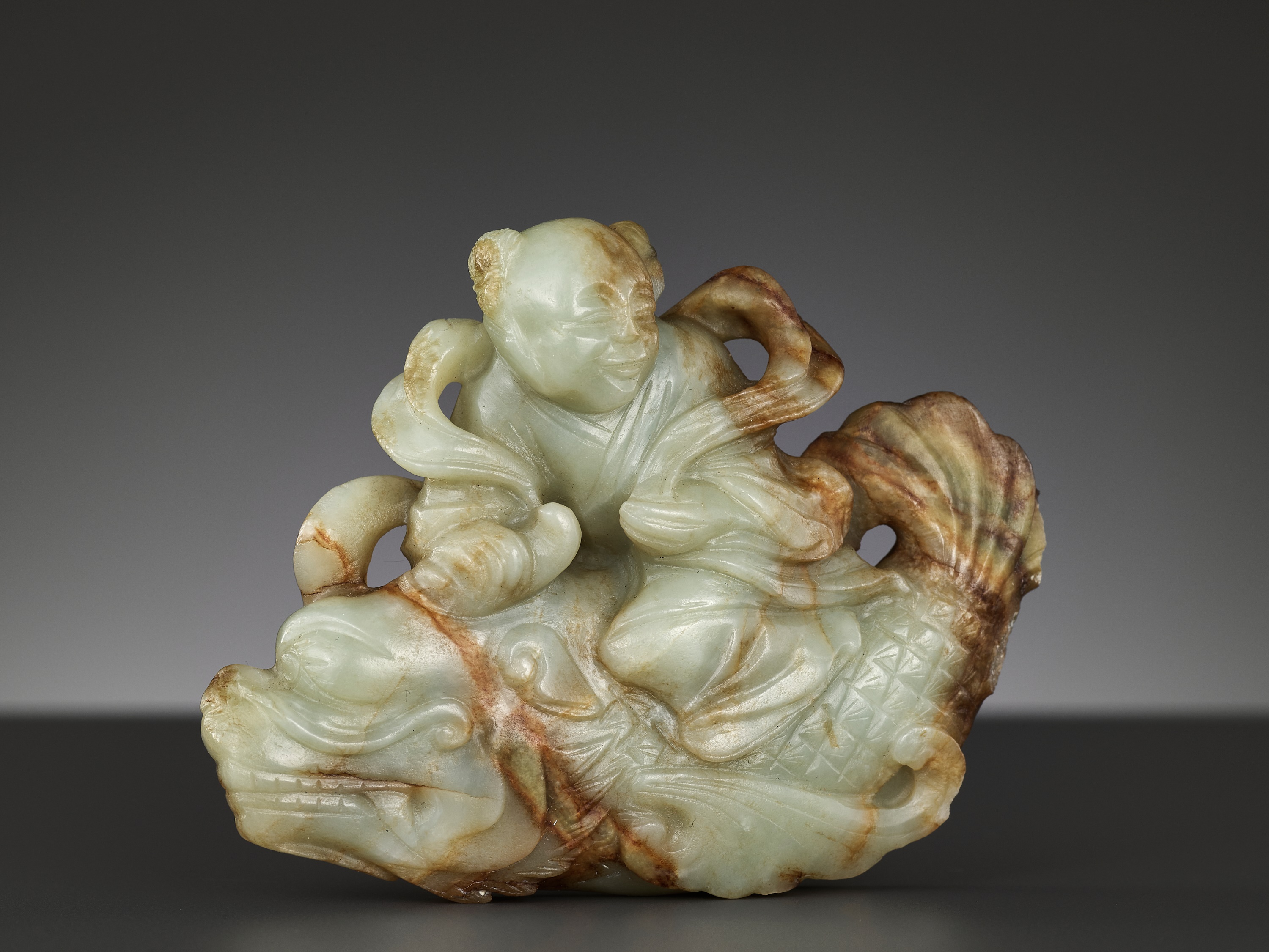 A CELADON AND RUSSET JADE FIGURE OF A BOY RIDING A DRAGON-CARP, 17TH-18TH CENTURY - Image 6 of 13