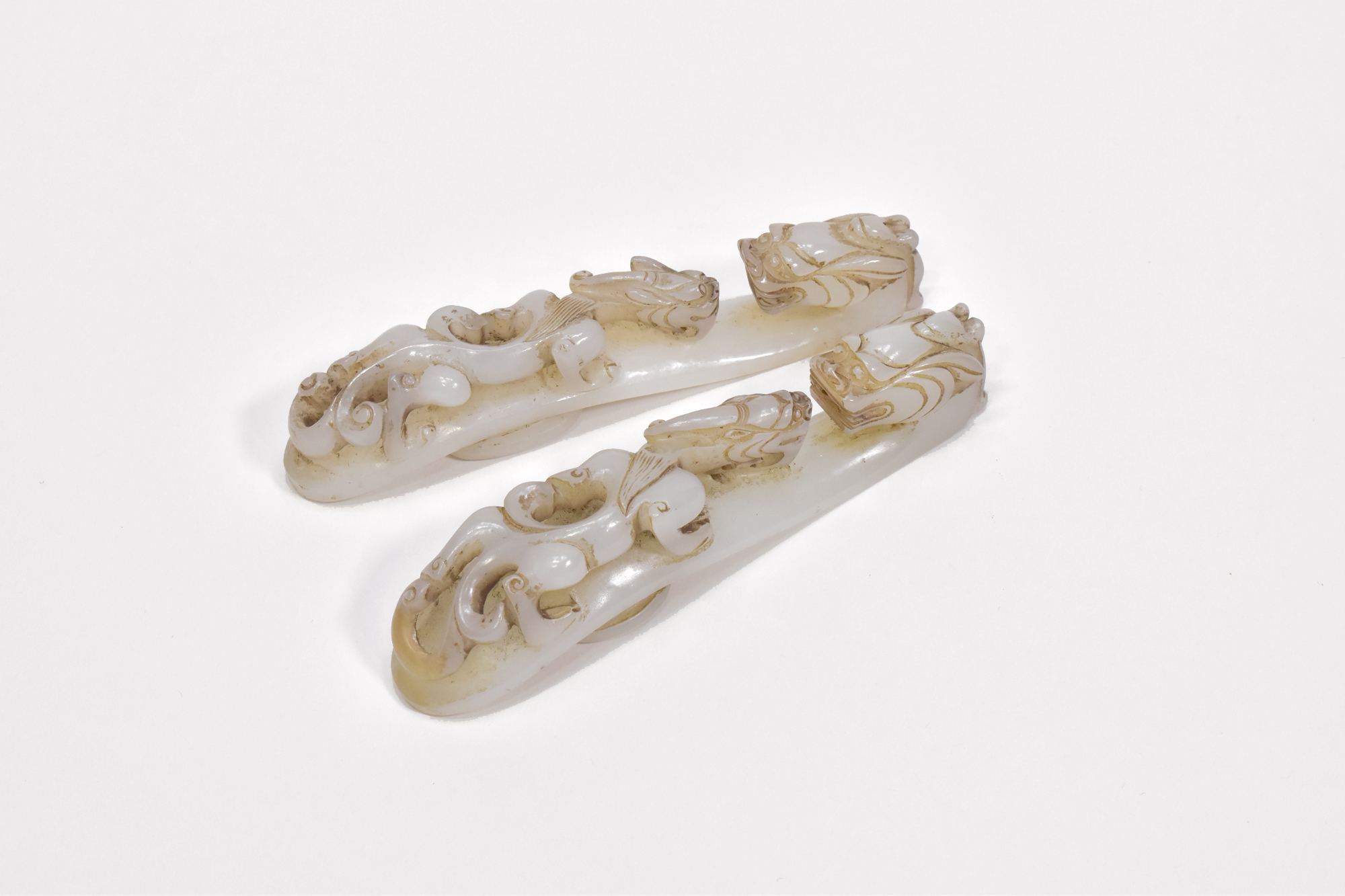 A PAIR OF CHINESE PALE CELADON JADE ‘DRAGON’ BELT HOOKS, QING DYNASTY, 19TH CENTURY