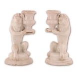 Coppia di candelieri in maiolica bianca conformati in guisa di leone, stante a sorreggere un vaso.