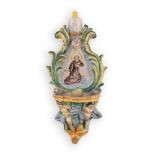 Acquasantiera in maiolica con decorazioni a rilievo e l'effigie di un Santo Francescano.