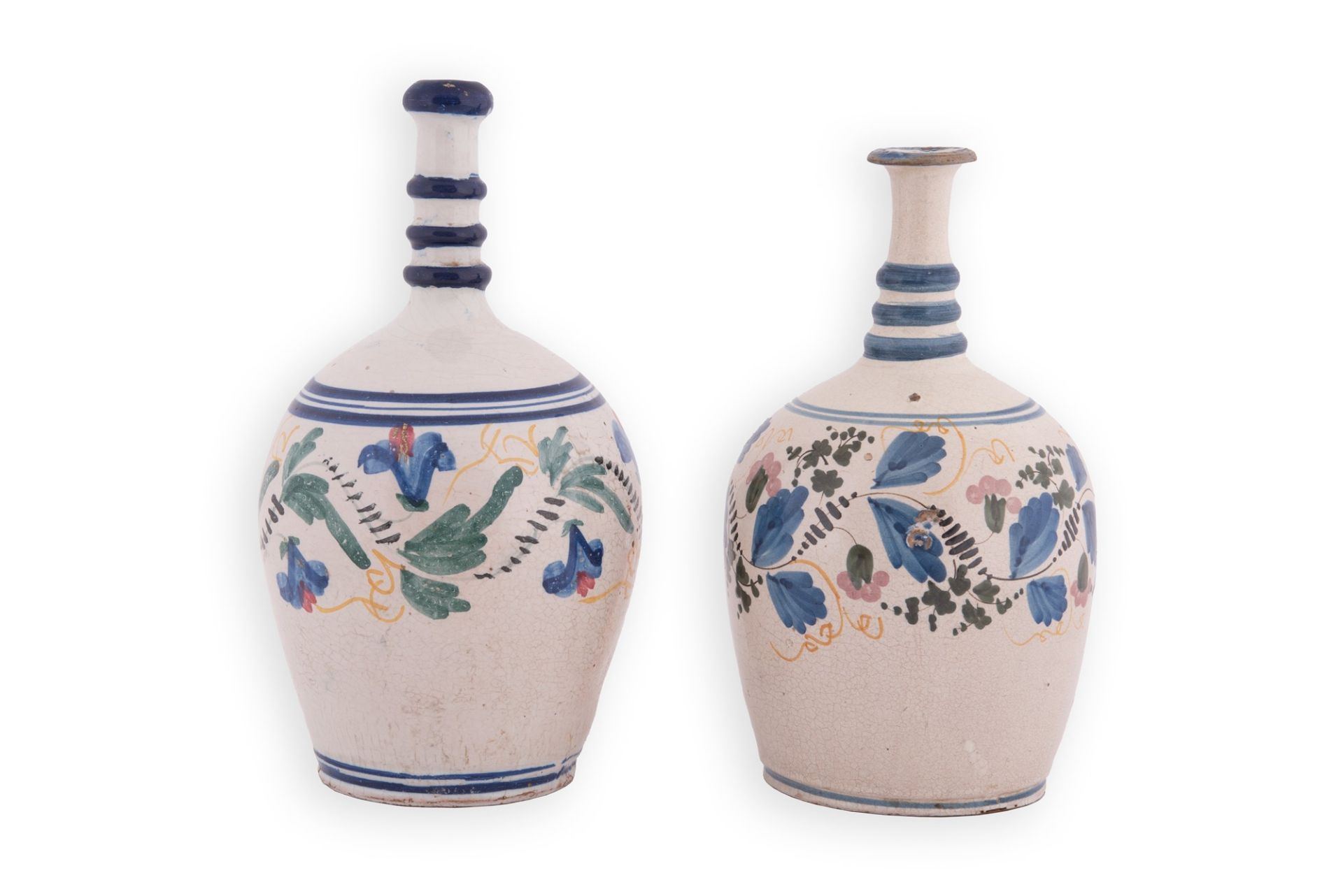 Due bottiglie in maiolica a fondo bianco. Corpo ovoidale decorato i policromia con motivi floreali. 
