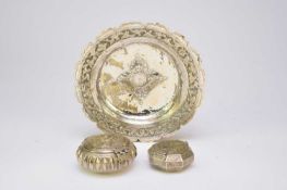 A Balinese embossed silver dish together with two similar powder/shot flasks