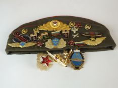 A Russian sidecap with twenty-two badges attached plus four loose Russian badges