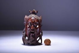 A South East Asian carved wood wall mask and a carved walnut shell