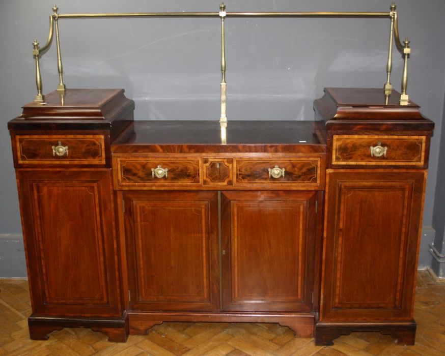 A Regency mahogany, satinwood crossbanded and strung sideboard. The brass rail overdrop centre,
