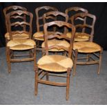 A set of seven late 19th century French provincial oak ladder back dining chairs, each with florally