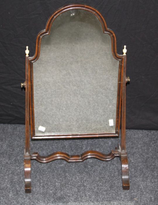 An Edwardian mahogany toilet mirror, the shouldered arched plate within fluted tapering horns with