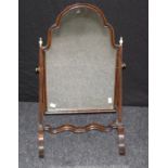 An Edwardian mahogany toilet mirror, the shouldered arched plate within fluted tapering horns with