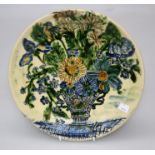 A studio pottery charger glazed with a decoration of a vase of flowers by Peter Thomas inscribed