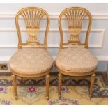 A pair of French Louis XVI style gilt wood and upholstered saloon chairs, circular backs with ornate