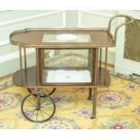 An early 20th century oak drinks trolley, the shaped top with a central moulded glass insert and