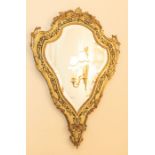 An early 20th century gilt and brass cartouche shaped mirror 87cm x 60cm  Please note this item is