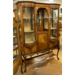 An Edwardian mahogany glass display cabinet, having an open central shelf with bevelled mirror,