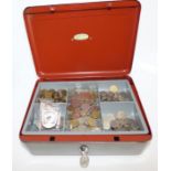 A large cash box with key and a collection of mostly foreign coins and some crowns