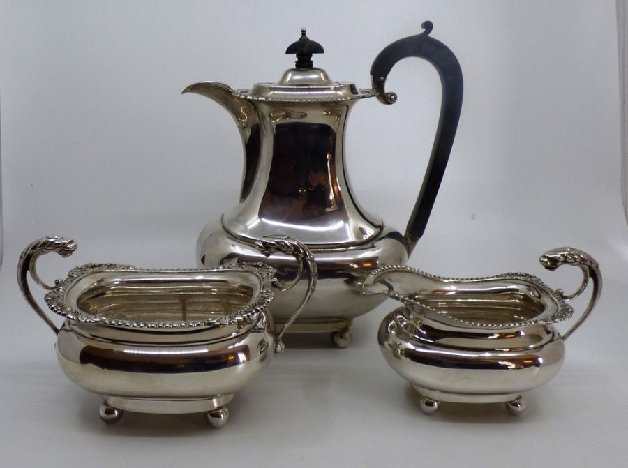 An Edwardian silver three piece coffee service of rounded baluster form on ball feet, comprising