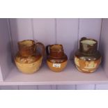 A good collection of three salt glazed stone ware, twin toned pottery jugs in Doulton style, circa