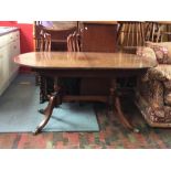 A decorative mid Century Regency effect dining table, the rounded ends cross banded raised on shaped
