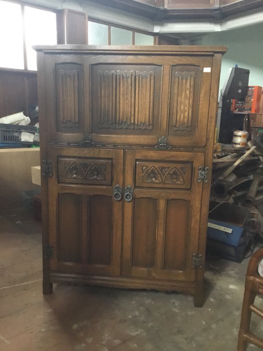 An Old Charm oak drinks cabinet, 3 panels of linenfold to upper hand which pulls open to reveal