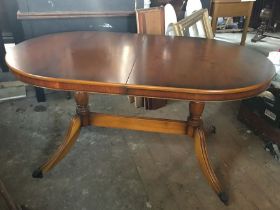 A reproduction walnut veneer twin pedestal extending dining table, fluted splayed legs with paw feet