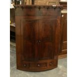 A george III flame mahogany bow fronted corner cabinet, moulded cornice with acorn drop