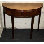 A late George III mahogany card table, the demi lune foldover top raised on fluted tapered legs, top