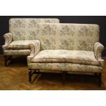 A pair of George III mahogany framed three seater settees upholstered in leaf pattern light coloured