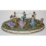 A large Sitzendorf porcelain group of six dancing maidens in a formal flower garden, on gilded