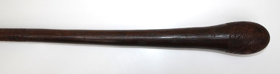 A wooden club with incise carved head and shaft, 89cm