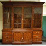 A large George III style figural mahogany breakfront library bookcase, the moulded case over four