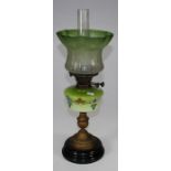 An Edwardian paraffin lamp, with florally etched green glass shade and painted reservoir on gilded