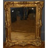 An ornate gilt composite framed wall mirror with rectangular bevelled plate, 102 x 79cm