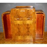 A 1930's Art Deco walnut cocktail cabinet, the rising top and fall front enclosing mirrored interior