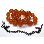 A graduated amber type necklace(subject to testing) together with a faceted jet bead and gilt