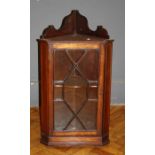 A small George III style mahogany hanging corner cabinet enclosed by an astragal glazed panel
