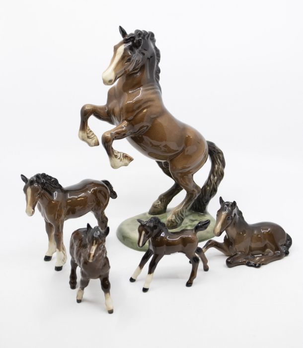 A rearing Beswick horse, together with four foals including a shire foal and shetland foal