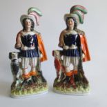 Two Staffordshire figures of a huntsmen with feathers in their hats, rabbit on shoulders and dogs (