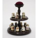 A collection of 15 Royal Crown Derby thimbles on a wooden display case stand with a pin cushion (all